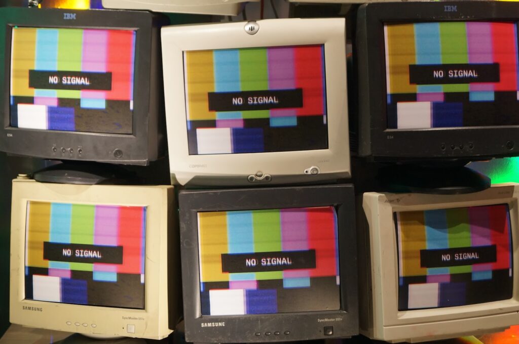 A photo of many tv and computer screens, each on of them showing "no signal" appearing to be broken.