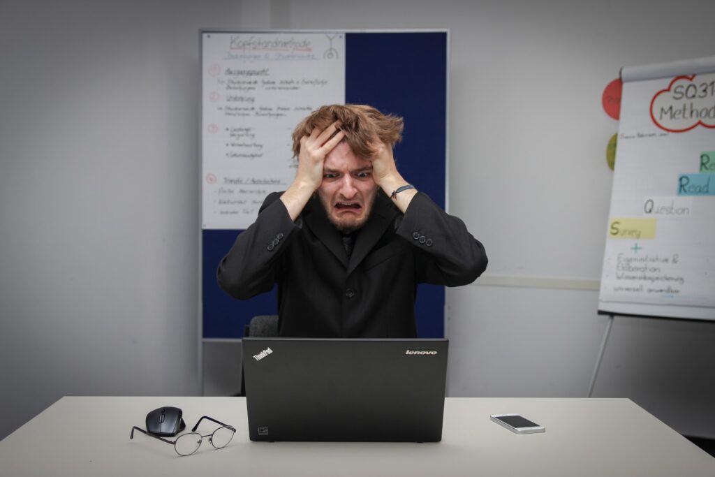 A photo of a disgruntled man sitting at his laptop, looking for SIM card packages in Turkey and holding his head in frustration.